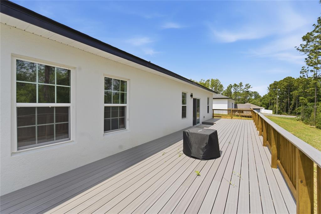 A long, light-gray composite deck runs along the side of a white stucco house — 785 MARION OAKS TRL UNIT 785, OCALA, FL