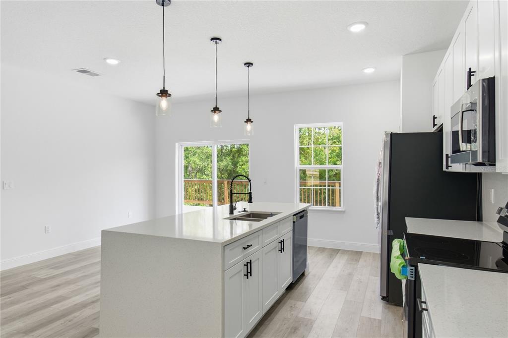 A kitchen features a white island with a sink, light wood flooring, and white cabinets — 785 MARION OAKS TRL UNIT 785, OCALA, FL