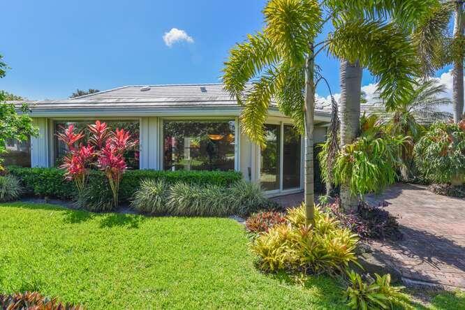 A single-story house exterior with a green lawn, palm trees, and a brick walkway — 437 French Royale Circle, Atlantis FL 33462, ATLANTIS, FL