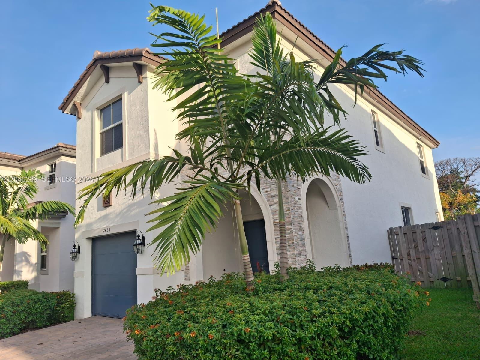 A two-story stucco house with a garage, a palm tree, and a stone-accented entryway — 2439 NW 131st Cir, Miami FL 33167, MIAMI, FL