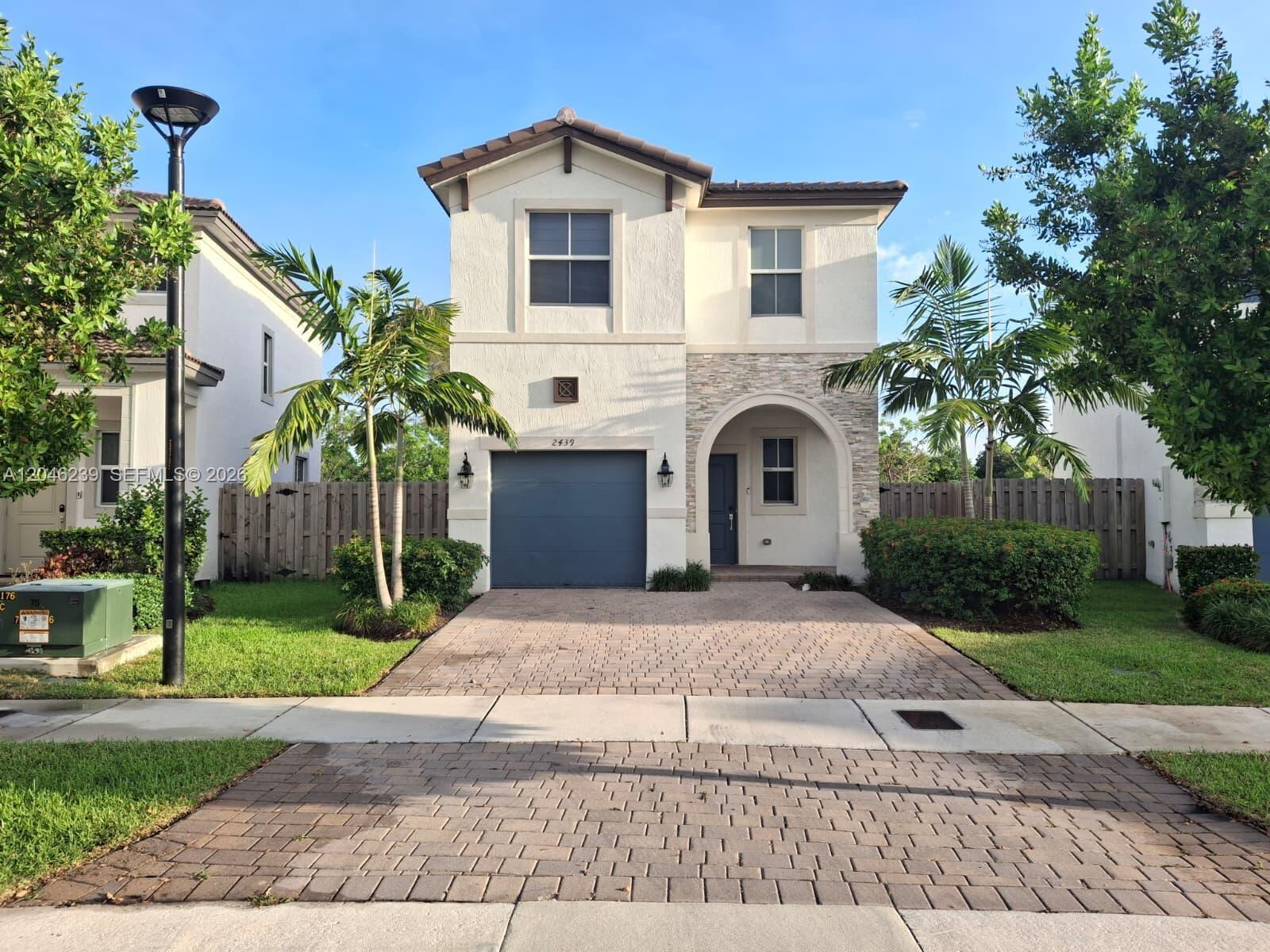 A two-story house with a paved driveway, a single-car garage, and palm trees in front — 2439 NW 131st Cir, Miami FL 33167, MIAMI, FL