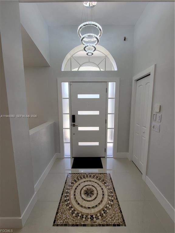 An entryway features a modern chandelier, a white door with glass inserts, and mosaic flooring — 237 SW 47TH ST # 0, Cape Coral FL 33914, CAPE CORAL, FL
