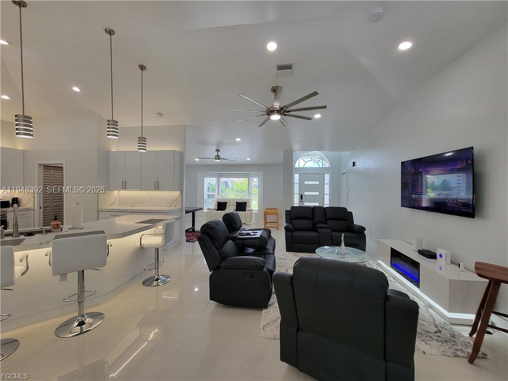 An open-concept living room and kitchen feature white tile floors, modern cabinetry, and black furniture — 237 SW 47TH ST # 0, Cape Coral FL 33914, CAPE CORAL, FL