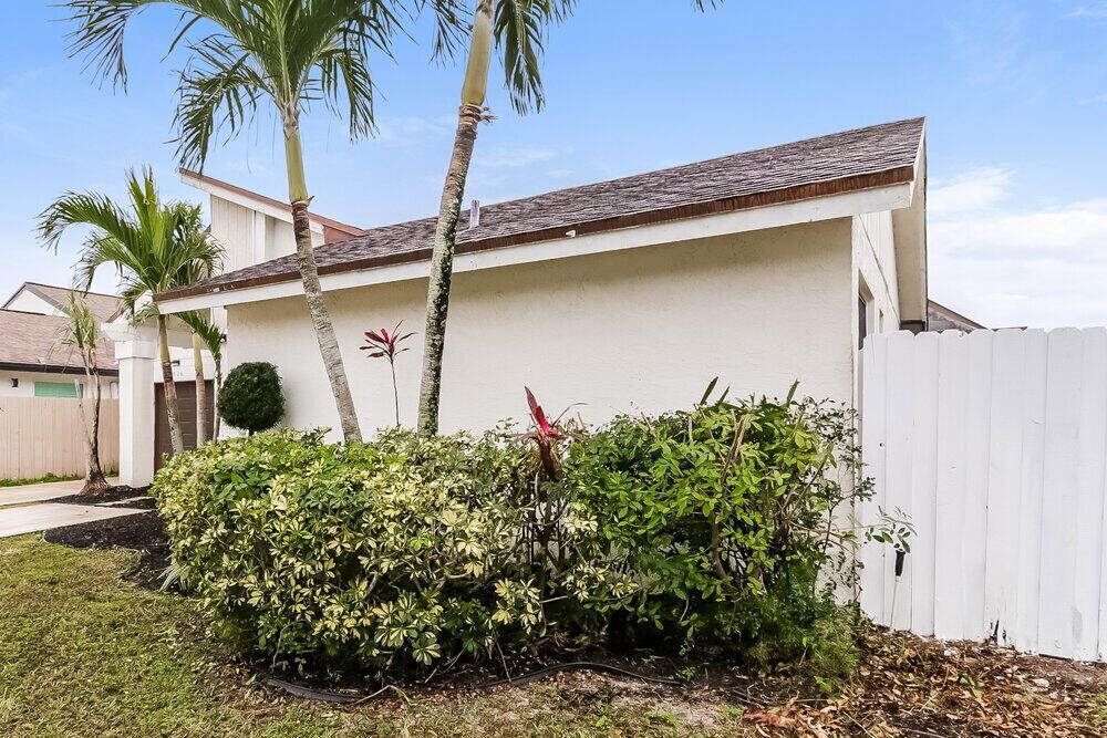 A white stucco house exterior features a shingled roof, palm trees, and a privacy fence — BOCA RATON, FL