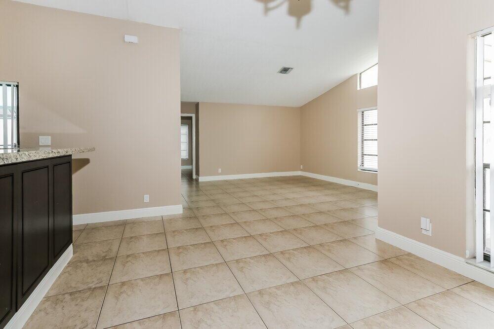 An empty room with beige walls, tile flooring, and large windows — BOCA RATON, FL
