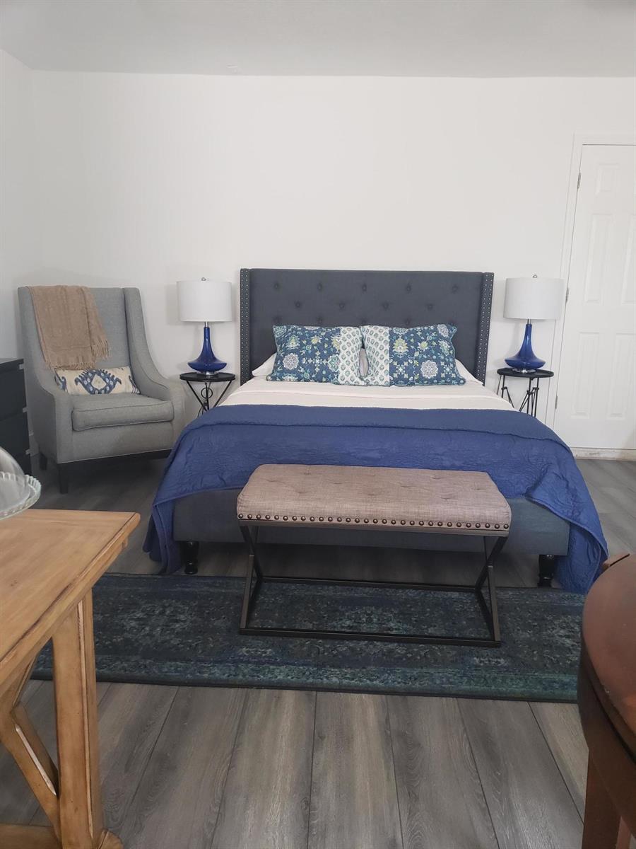 A bedroom features a tufted gray headboard, blue bedding, a gray armchair, and a bench — 14313 N Flora Lane # A, Wellington FL 33414, WELLINGTON, FL