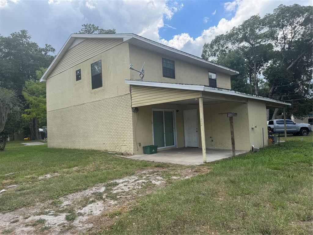 A two-story house with a yellow brick and stucco exterior features a covered concrete patio — 221 S CYPRESS WAY, CASSELBERRY, FL
