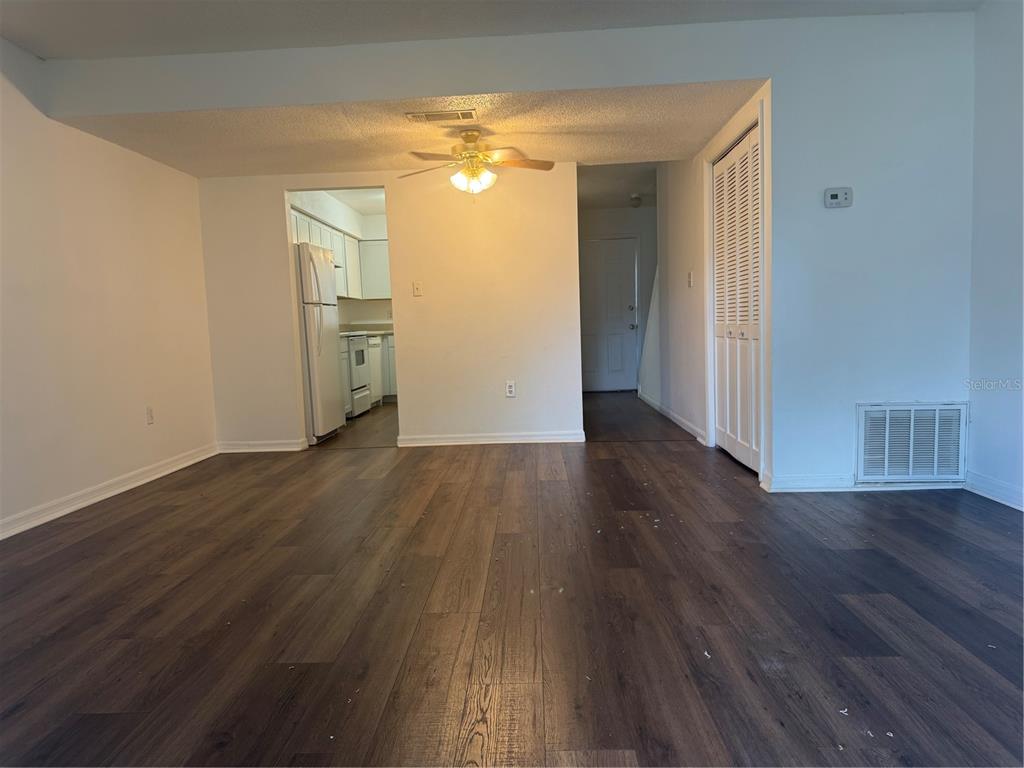 An interior view of a living area with dark wood-look flooring and a ceiling fan — 221 S CYPRESS WAY, CASSELBERRY, FL