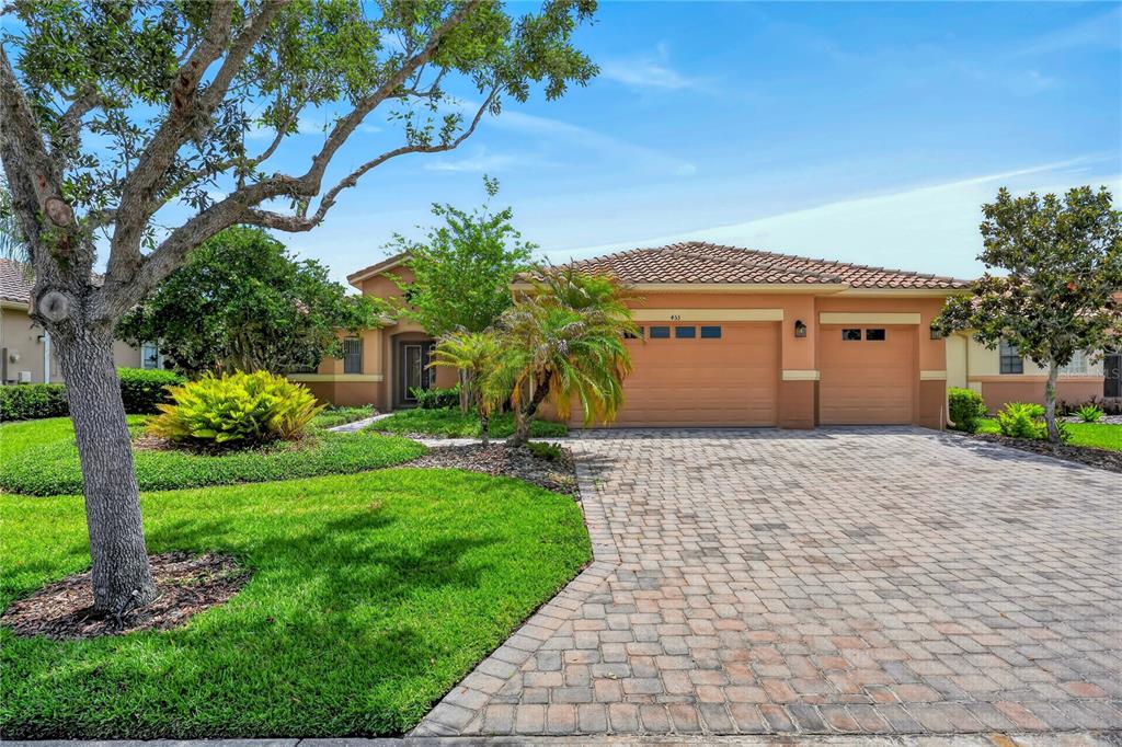 A single-story house with a tan stucco exterior, a tile roof, and a paved driveway — 453 SORRENTO RD, KISSIMMEE, FL