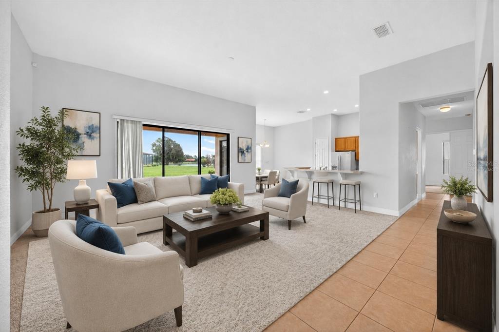A living room with a beige sofa, two armchairs, and a view of a backyard — 453 SORRENTO RD, KISSIMMEE, FL