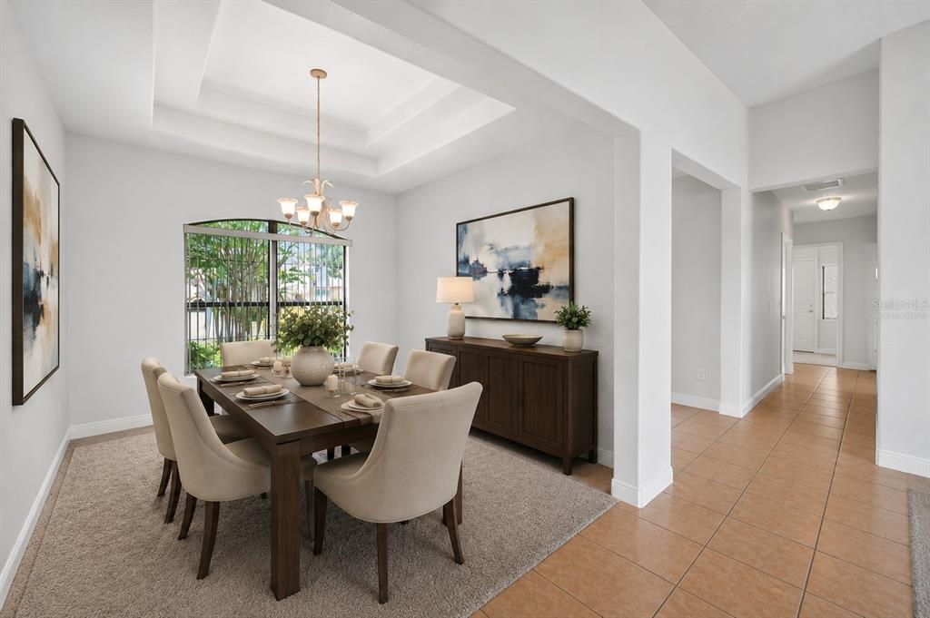A dining room with a tray ceiling, chandelier, wooden table, and beige upholstered chairs — 453 SORRENTO RD, KISSIMMEE, FL