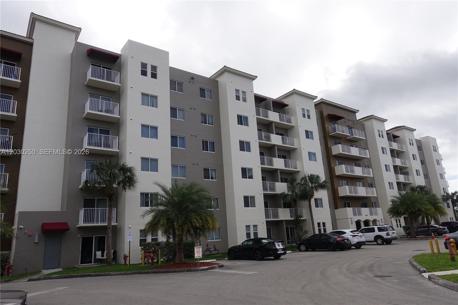 The exterior of a multi-story apartment building features balconies and a parking lot — CUTLER BAY, FL