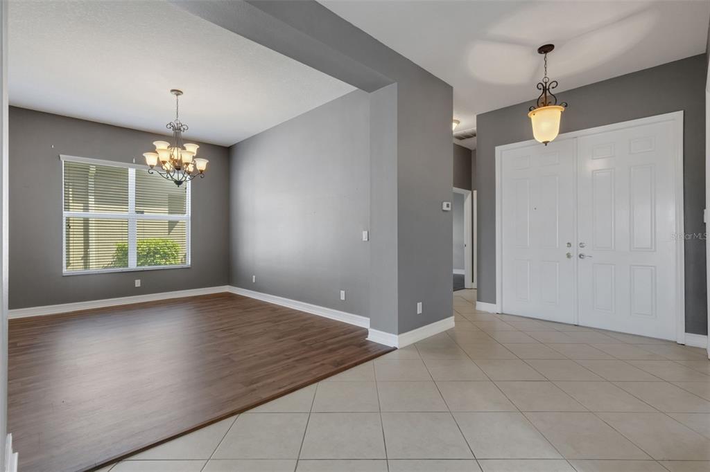 A dining area with wood-look flooring and a chandelier adjacent to a tiled entryway — 15841 COBBLE MILL DRIVE, WIMAUMA, FL