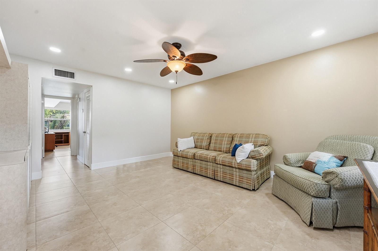A living room features beige tile floors, a ceiling fan, and a plaid sofa — 566 Piedmont L, Delray Beach FL 33484, DELRAY BEACH, FL