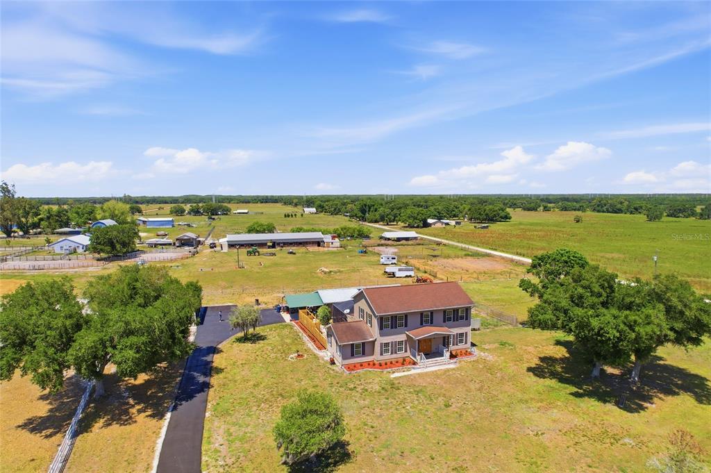An aerial view shows a two-story house with a brown roof on a rural property — 15470 STATE ROAD 62, PARRISH, FL