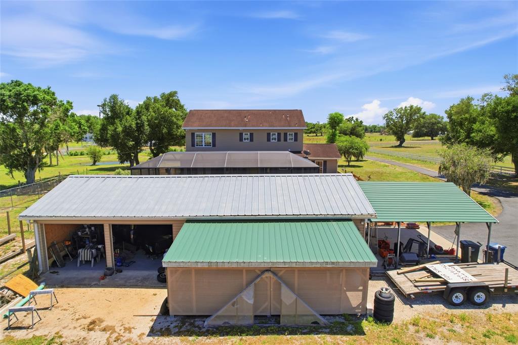An aerial view shows a house with a large metal-roofed garage and attached carport — 15470 STATE ROAD 62, PARRISH, FL
