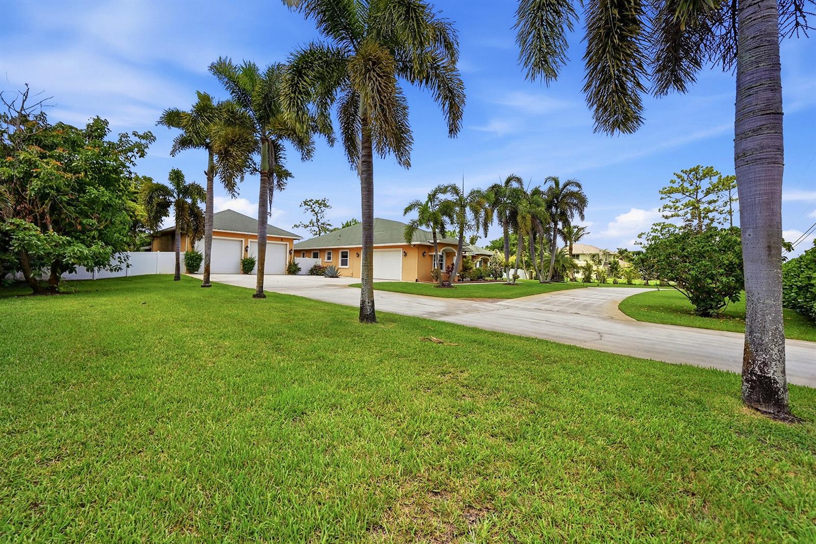 A yellow house with a green roof and palm trees sits behind a large lawn — 14310 N 85th Rd Road N, FL 33470, FL
