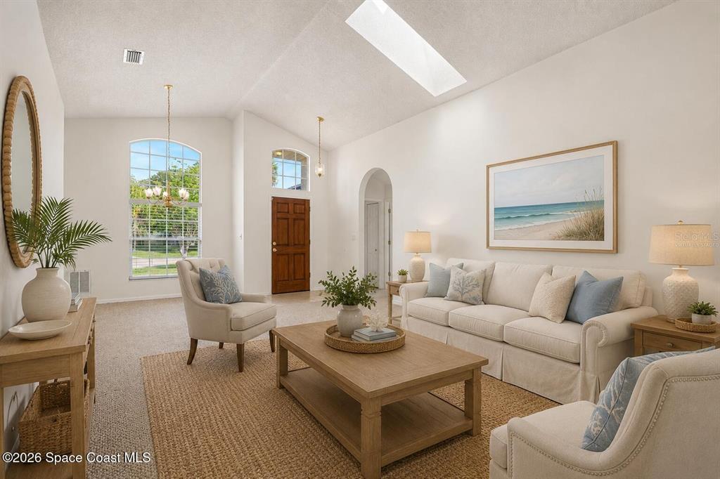 A bright living room features a vaulted ceiling, a skylight, and neutral coastal-style furniture — 760 MONDAY COURT, COCOA, FL