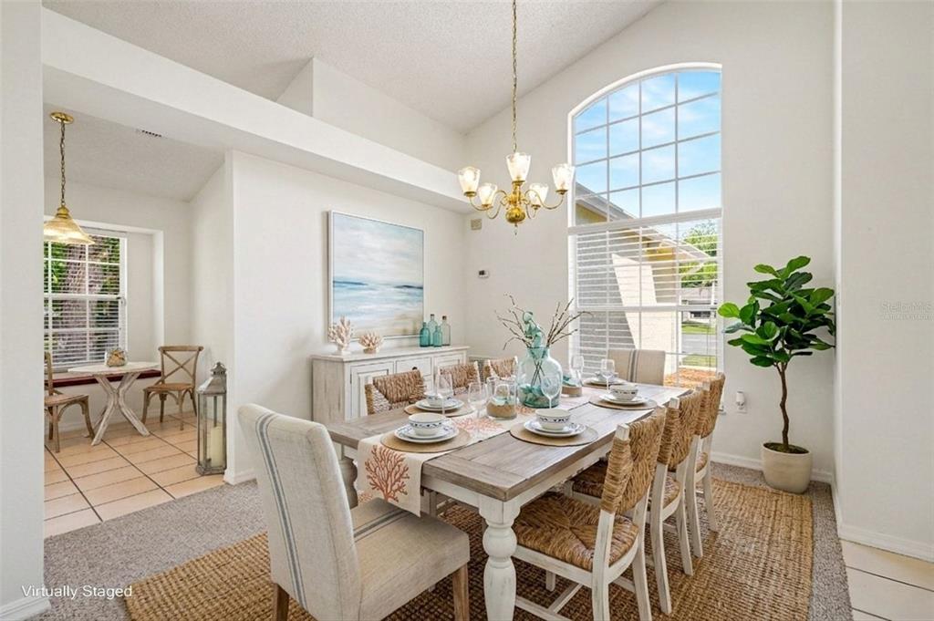A dining room with a wooden table, woven chairs, a chandelier, and a large arched window — 760 MONDAY COURT, COCOA, FL