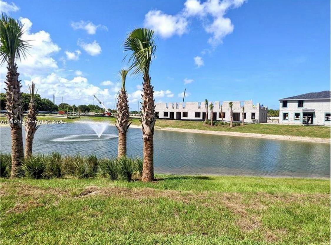 A view of a pond, palm trees, and a building under construction — 5629 Mentmore Dr, Mangonia Park FL 33407, MANGONIA PARK, FL