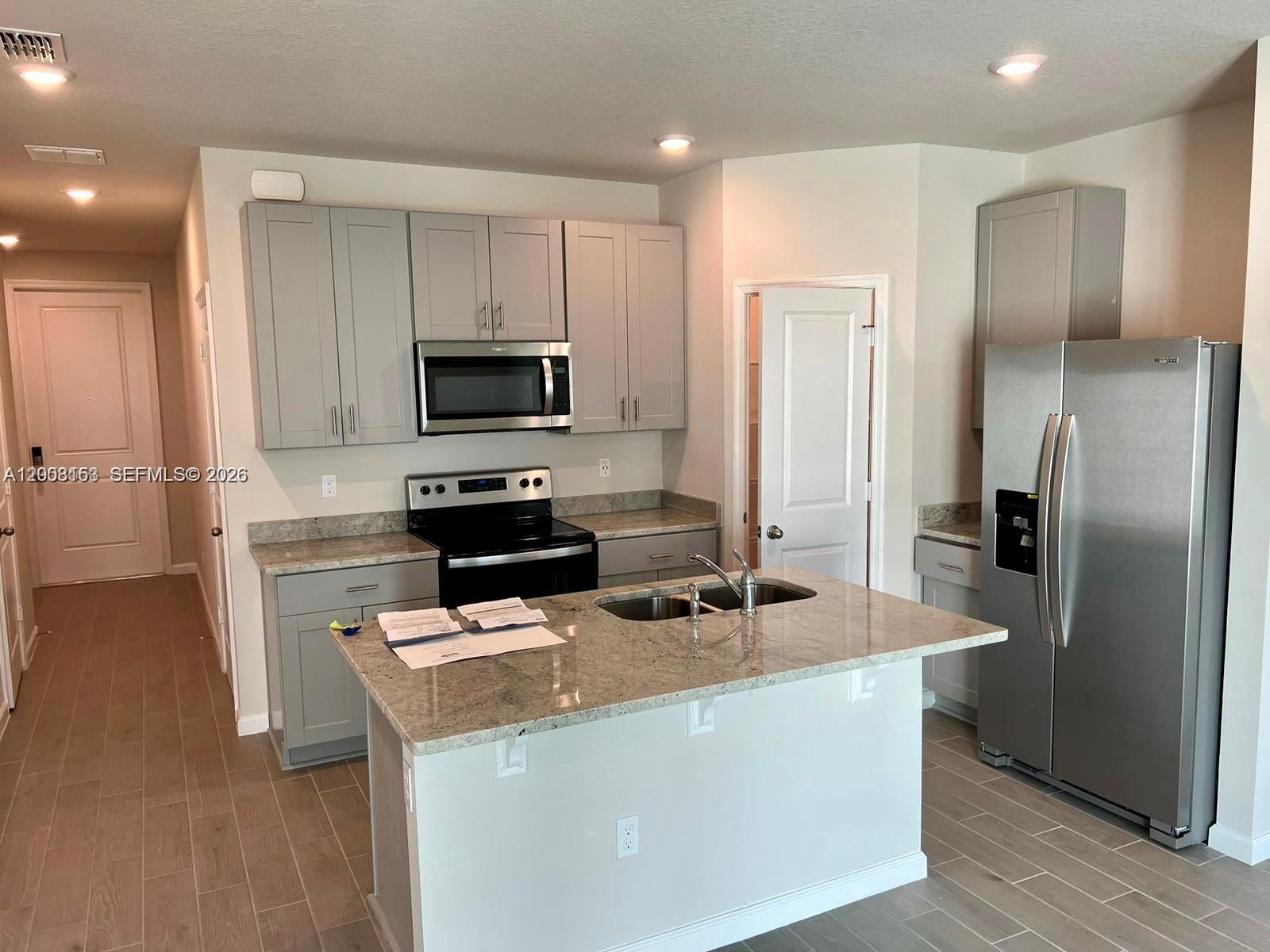 A kitchen features gray cabinets, stainless steel appliances, and a granite-topped island — 5629 Mentmore Dr, Mangonia Park FL 33407, MANGONIA PARK, FL
