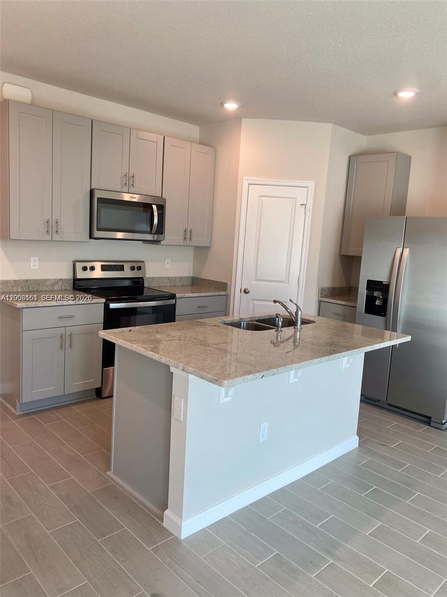 A kitchen features grey cabinets, stainless steel appliances, and a granite-topped island — 5629 Mentmore Dr, Mangonia Park FL 33407, MANGONIA PARK, FL