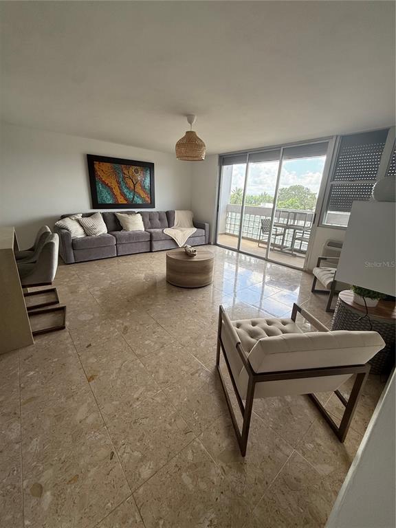 A living room features light tile flooring, a gray sectional sofa, and a glass balcony door — 3001 ave isla verde PLAZA DEL MAR UNIT 405, CAROLINA, PR