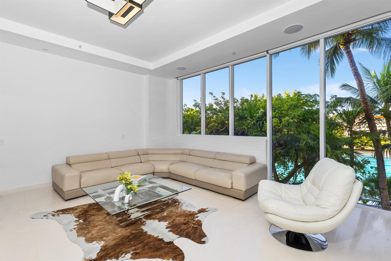 A modern living room features a beige sectional sofa, glass coffee table, and floor-to-ceiling windows — 1000 S Ocean Boulevard # 110, Boca Raton FL 33432, BOCA RATON, FL