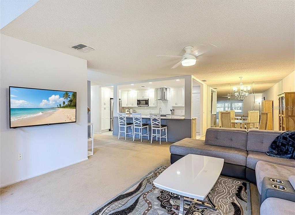 A living room with a gray sectional sofa, white coffee table, and an open kitchen — 11431 DOLLAR LAKE DRIVE UNIT 1, PORT RICHEY, FL