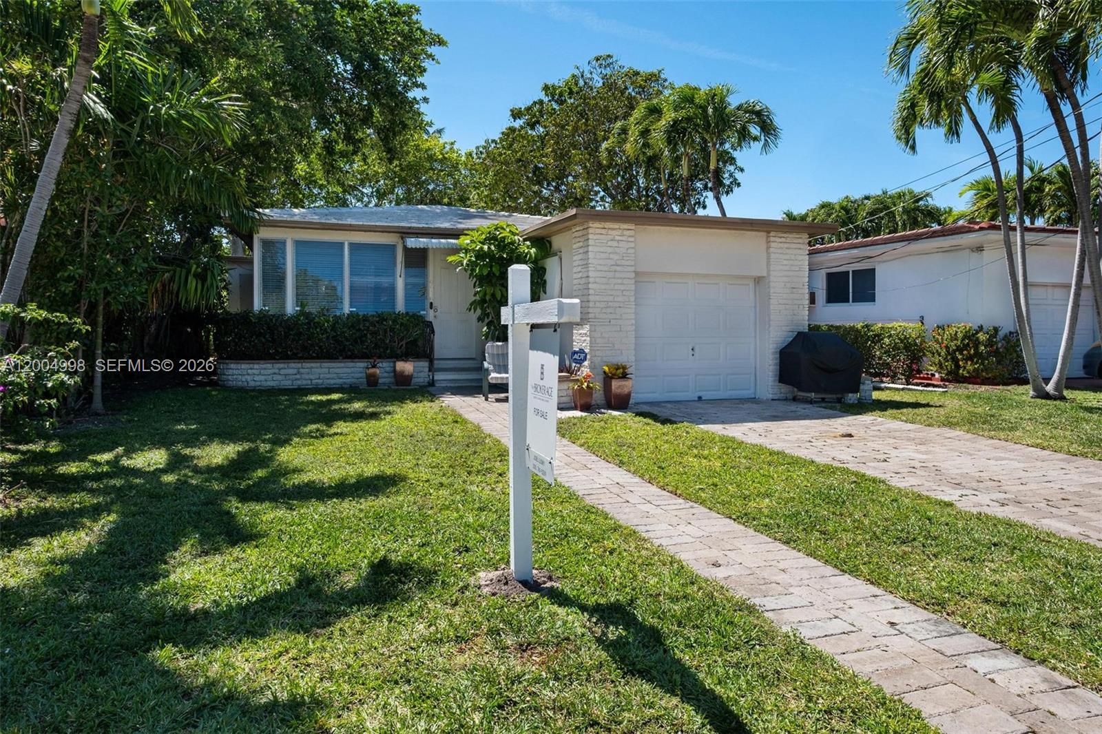 A single-story house with a white brick facade, a garage, and a paved walkway — 9516 Byron Ave, Surfside FL 33154, SURFSIDE, FL