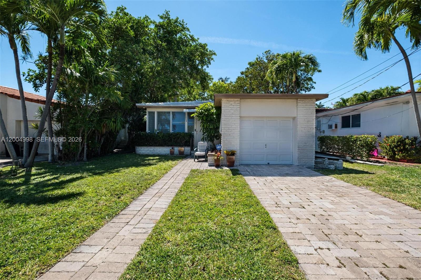 A single-story house with a white brick facade, a garage, and a paved driveway — 9516 Byron Ave, Surfside FL 33154, SURFSIDE, FL