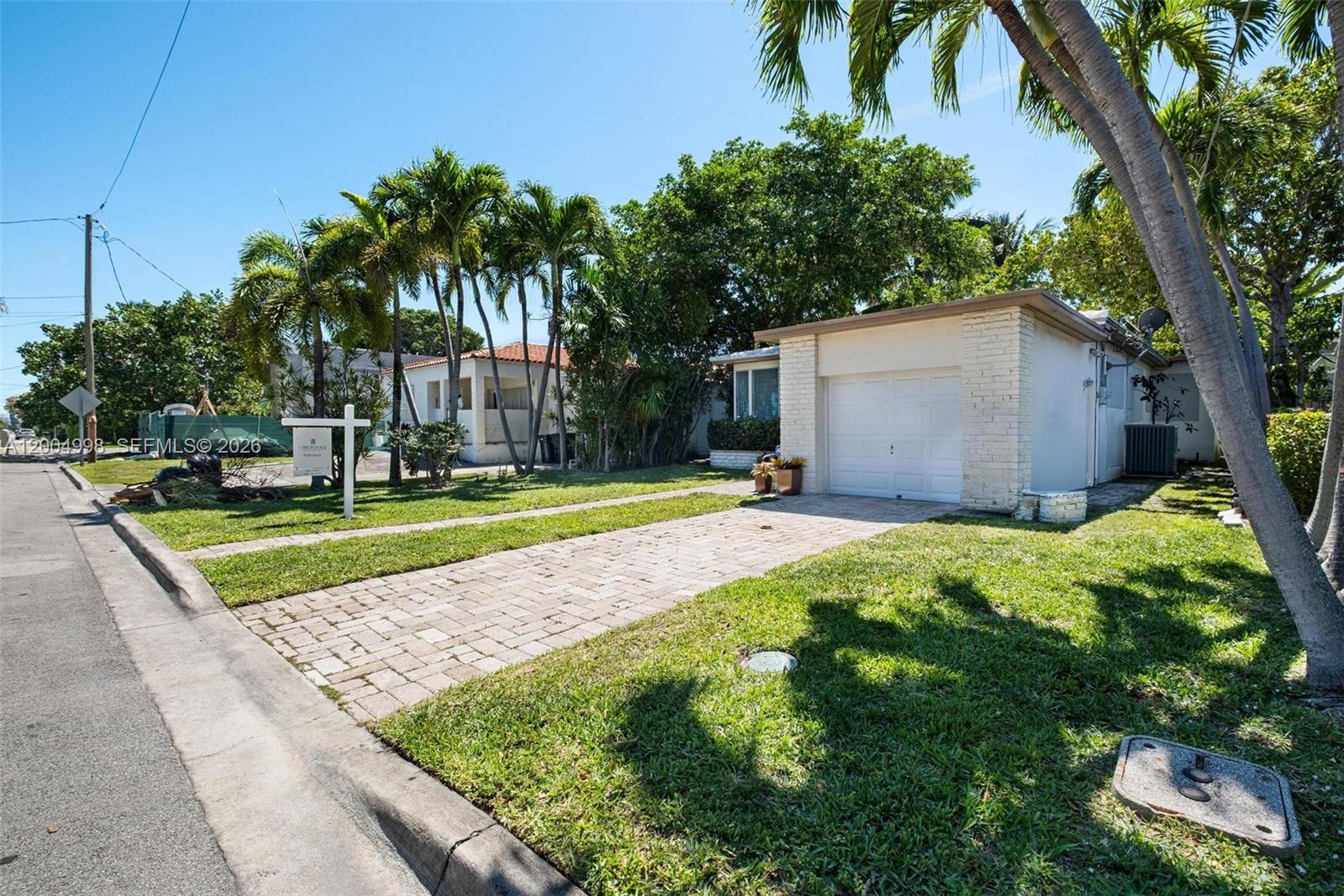A single-story house with a white brick garage and a paved driveway sits on a lawn — 9516 Byron Ave, Surfside FL 33154, SURFSIDE, FL