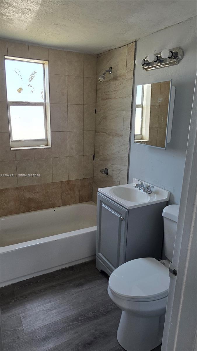 A small bathroom features a bathtub, a grey vanity, a toilet, and tiled walls — 7001 NW 15th Ave # 8, Miami FL 33147, MIAMI, FL