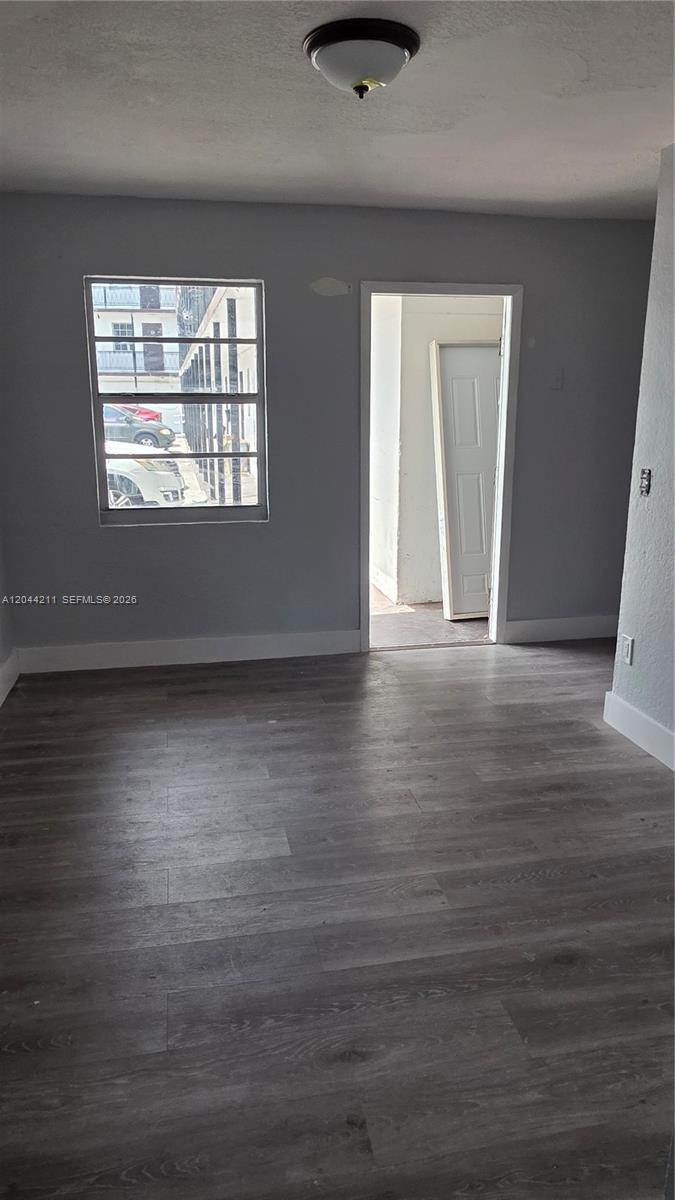 An interior room features gray walls, wood-look flooring, a window, and an open doorway — 7001 NW 15th Ave # 8, Miami FL 33147, MIAMI, FL