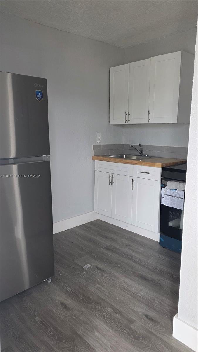A small kitchen features white cabinets, a butcher block countertop, and stainless steel appliances — 7001 NW 15th Ave # 8, Miami FL 33147, MIAMI, FL