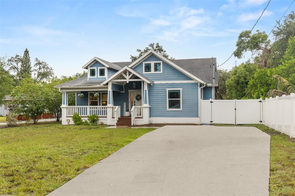 A blue-sided house with a front porch, dormer windows, and a concrete driveway — 6109 N 22ND STREET, TAMPA, FL