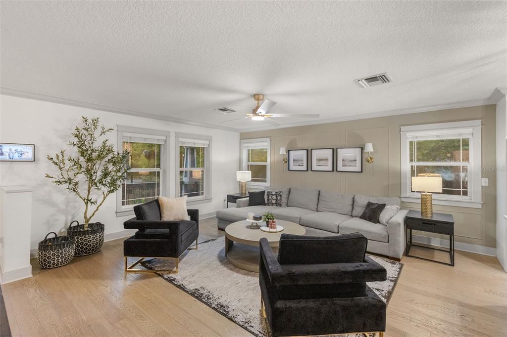 A living room features a gray sectional sofa, two black armchairs, and light wood flooring — 6109 N 22ND STREET, TAMPA, FL