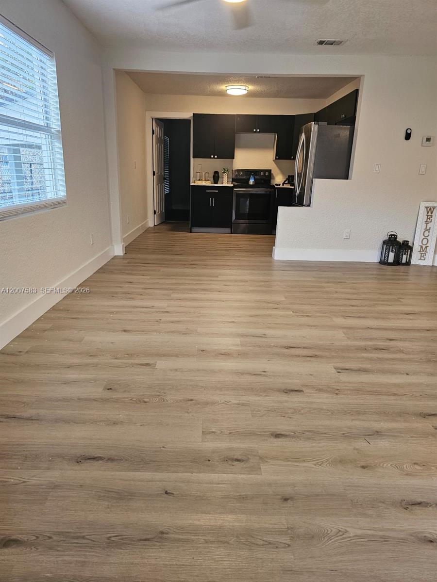 A kitchen with dark cabinets and stainless steel appliances opens into a living area — 1865 NW 45th St # 1, Miami FL 33142, MIAMI, FL