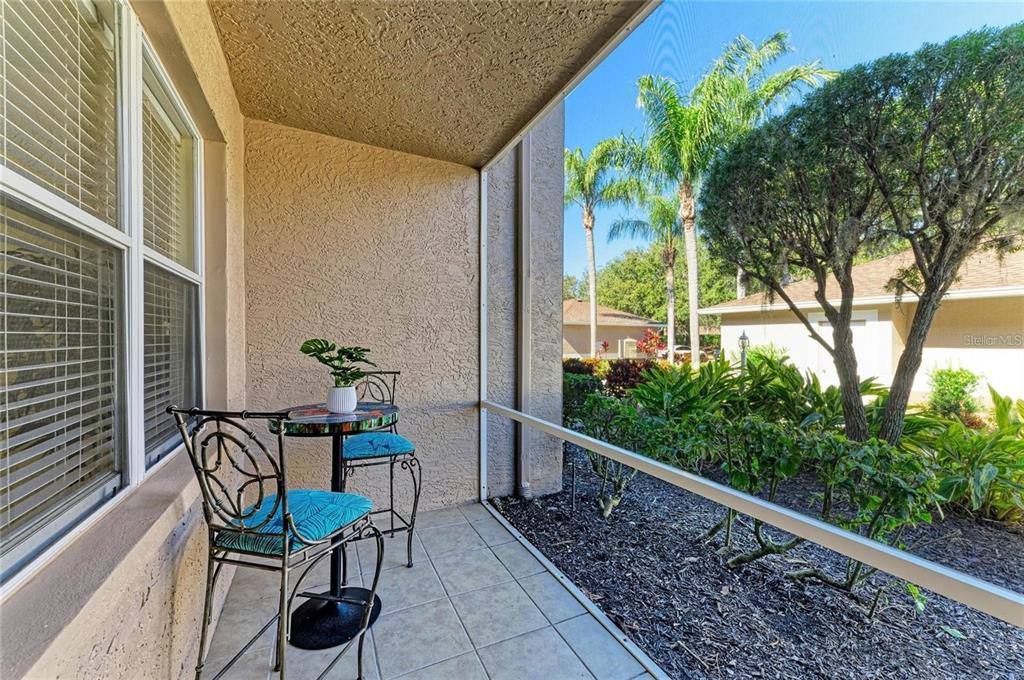 A screened-in patio with tiled flooring, a small bistro set, and a view of landscaping — 5350 HYLAND HILLS AVENUE UNIT 2512, SARASOTA, FL