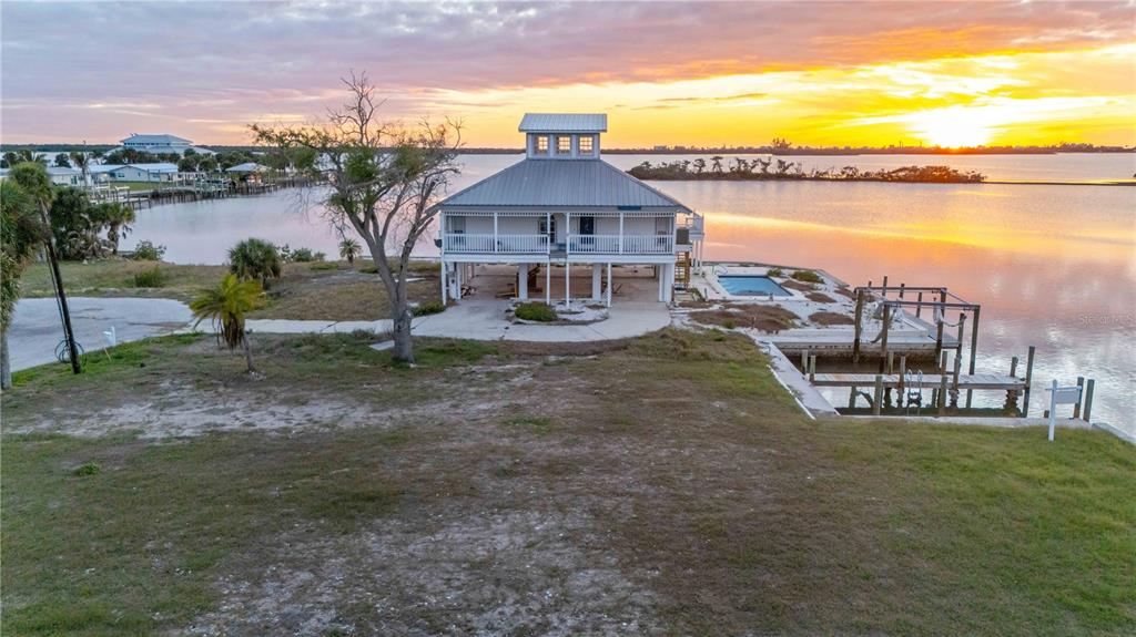 An elevated house with a metal roof and a pool sits on a waterfront lot — 1908 MICHIGAN AVENUE, ENGLEWOOD, FL
