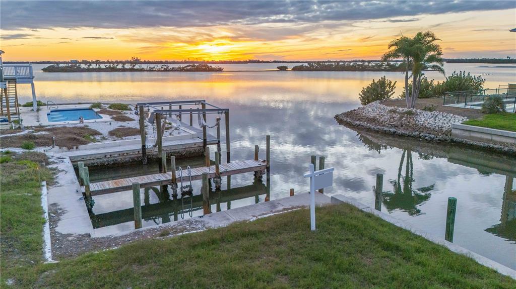 An aerial view of a waterfront property featuring a boat dock, pool, and sunset view — 1908 MICHIGAN AVENUE, ENGLEWOOD, FL