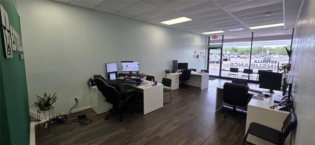 An office space features two white desks, black rolling chairs, and large windows facing outside — 856 N NOVA, DAYTONA BEACH, FL