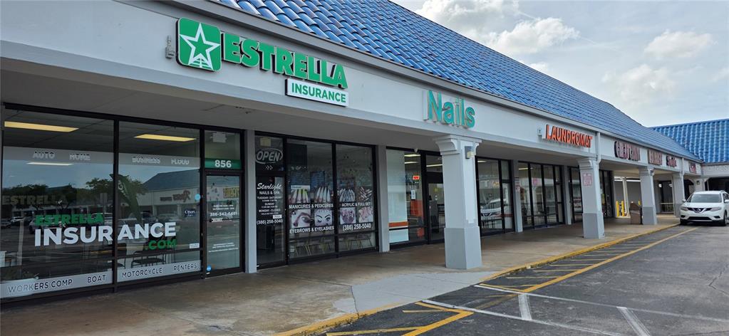 An exterior view of a commercial strip mall featuring an insurance agency and a nail salon — 856 N NOVA, DAYTONA BEACH, FL