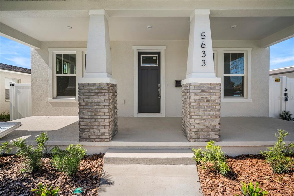 The front exterior of a house features a covered porch with two brick-based columns — 5633 DARTMOUTH AVENUE N, ST PETERSBURG, FL
