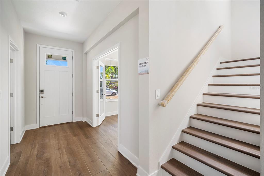 An entryway features wood-look flooring, a white front door, and a staircase with wooden treads — 5633 DARTMOUTH AVENUE N, ST PETERSBURG, FL