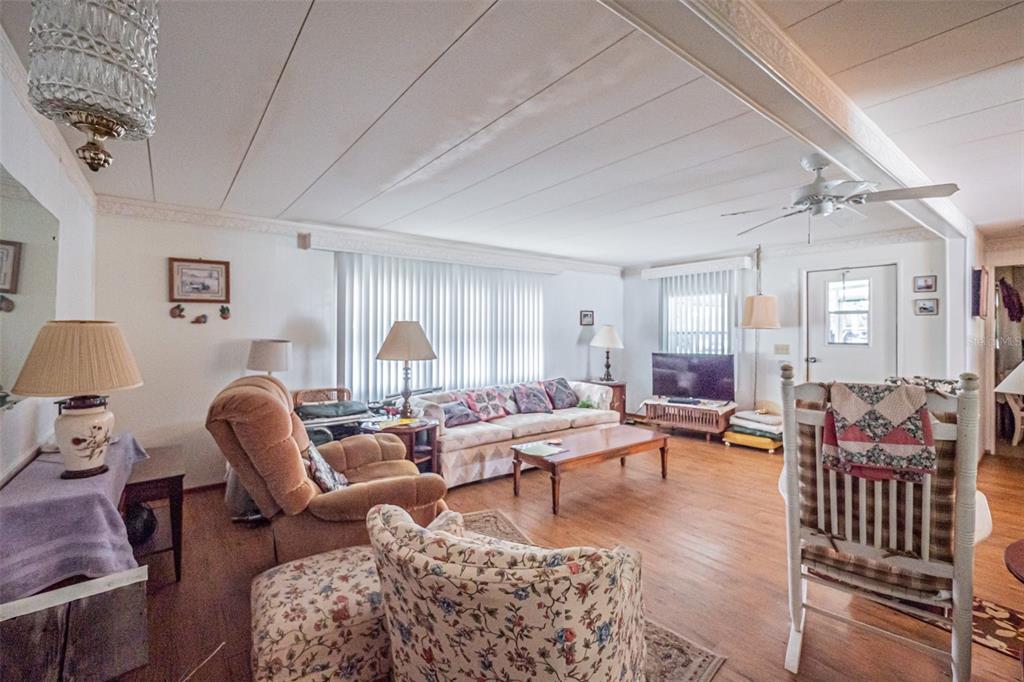 A living room features wood-look flooring, a ceiling fan, and various pieces of traditional furniture — 613 SANDPIPER DRIVE, LEESBURG, FL