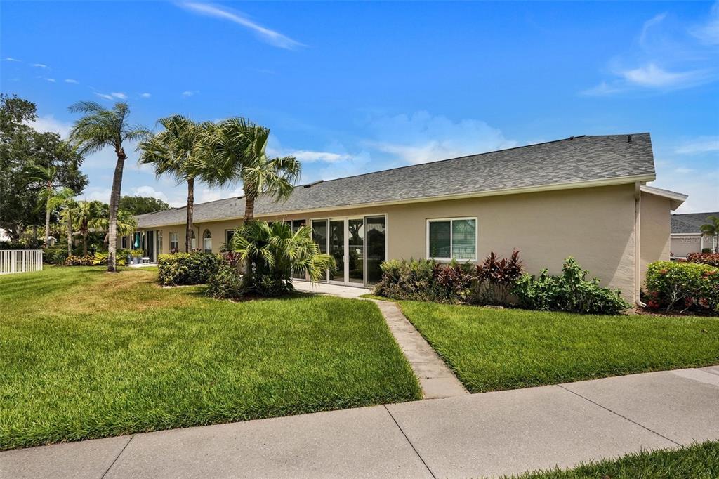 A single-story house exterior features a beige stucco facade, a shingled roof, and palm trees — 6929 STONEYWALK COURT, BRADENTON, FL