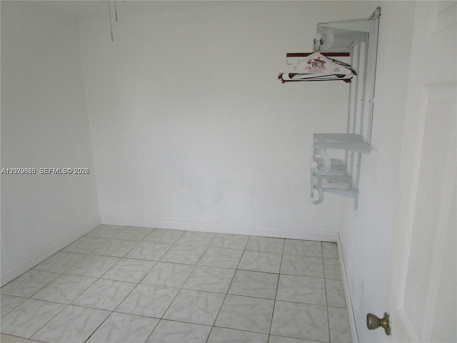 A small, empty closet features white walls, tiled flooring, and a white wire shelving unit — 115 NE 192nd St # 1, Miami FL 33179, MIAMI, FL