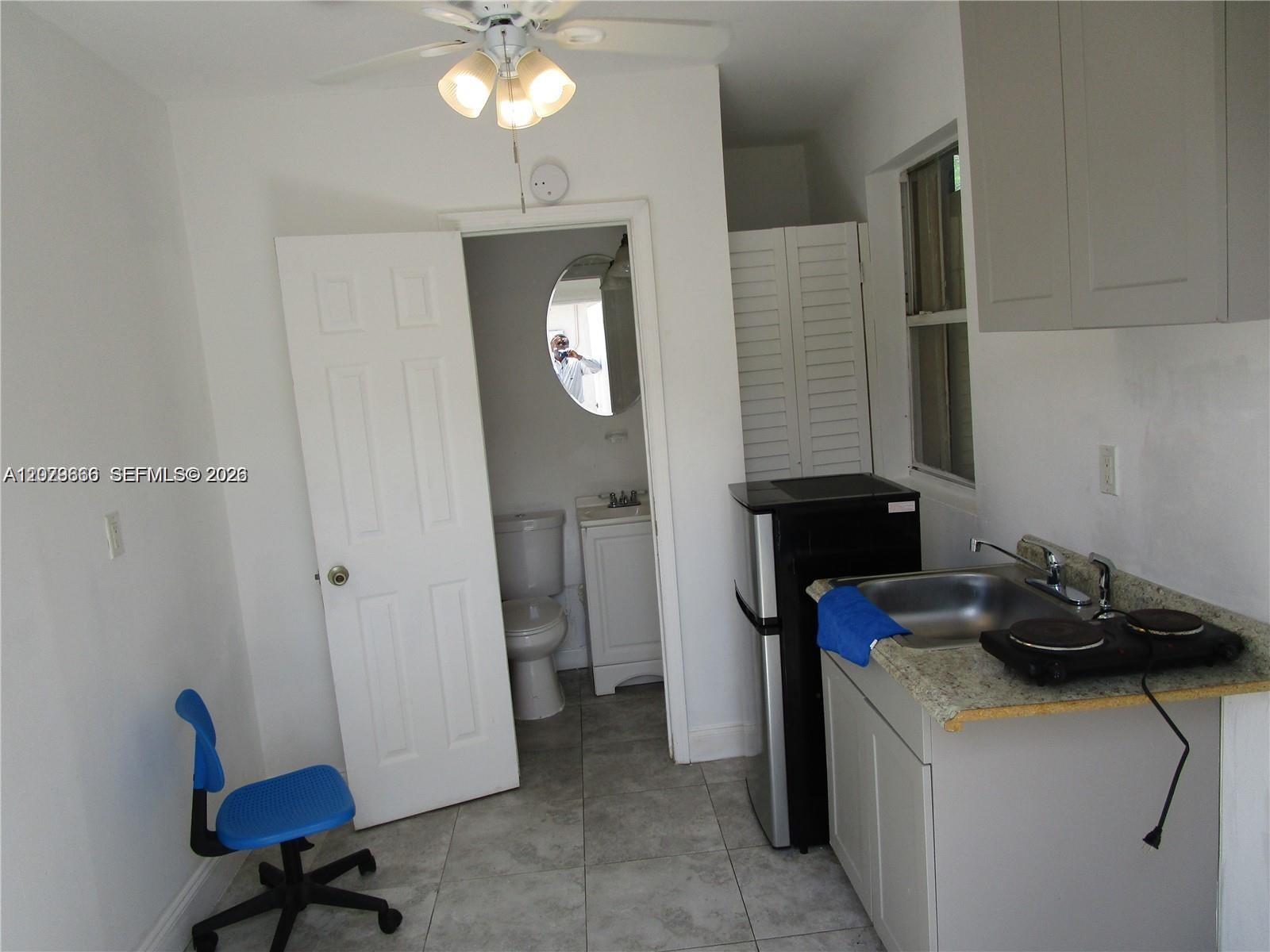 A small kitchenette with a sink and hot plate sits next to a bathroom door — 115 NE 192nd St # 1, Miami FL 33179, MIAMI, FL