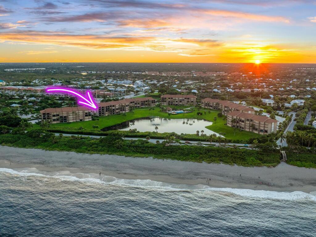 An aerial view of a beachfront condominium complex surrounding a central pond at sunset — 601 S Seas Drive # 106, Jupiter FL 33477, JUPITER, FL